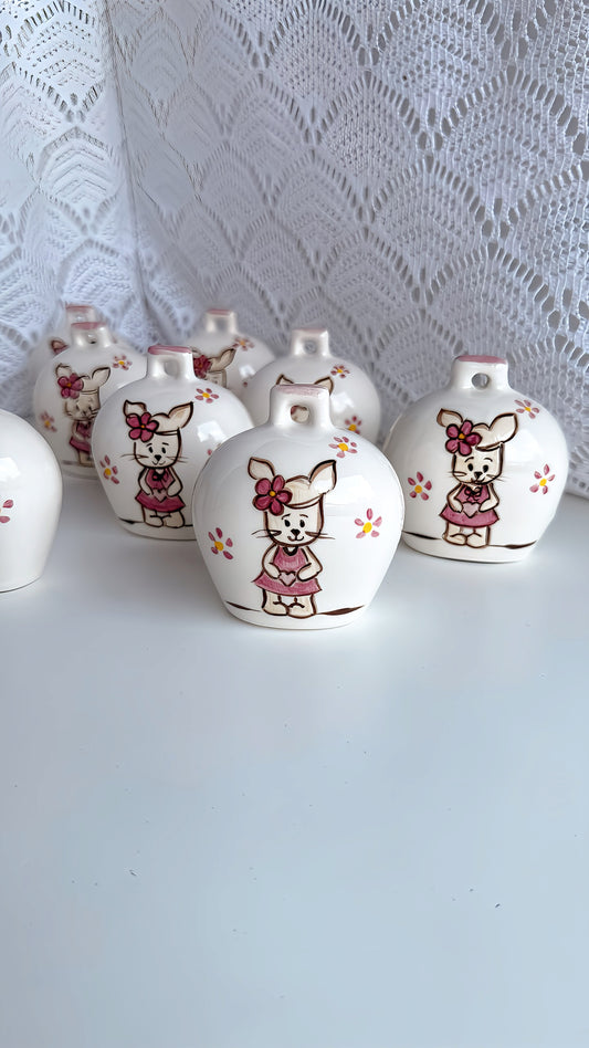 "Un battito di cuore in ceramica: le nostre bomboniere a campanella con coniglietta sono un inno alla dolcezza. Ogni pezzo, finemente dipinto a mano a Capri, cattura la delicatezza della coniglietta e la vivacità dei fiori. Perfette per Nascita e Battesimo, queste piccole opere d'arte da 6x7cm aggiungono un tocco di incanto e artigianalità italiana al tuo evento, diventando un ricordo prezioso che dura nel tempo."