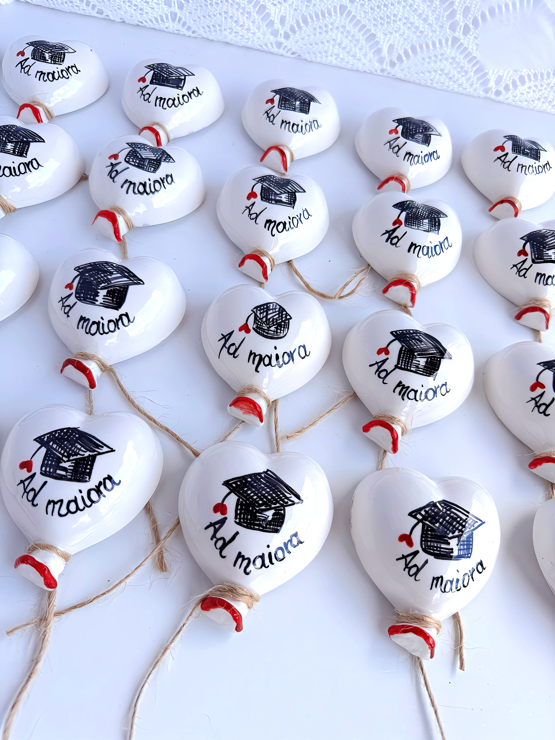  Composizione di diverse bomboniere laurea palloncino in ceramica (6x7 cm) su un tavolo, pronte per essere donate, simbolo di leggerezza e successo.