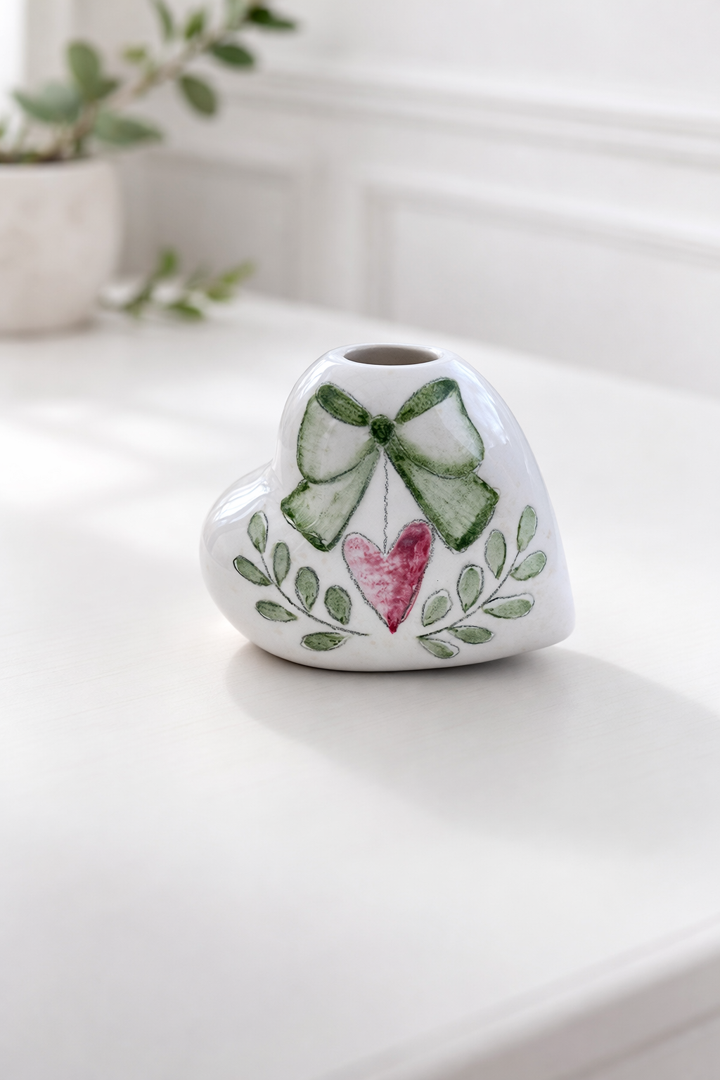 Profumatore in ceramica a forma di cuore decorato a mano con fiocco verde salvia, cuore rosa e motivo botanico, complemento d’arredo e bomboniera elegante.